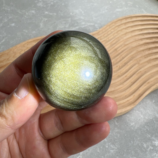 金曜石球

天然金曜石：擁抱內斂的耀眼

有時候，最迷人的光芒，往往藏在最深邃的黑暗裡。

如果說黑曜石是安靜的守護者，那麼金曜石（Golden Obsidian）則是那位在黑夜中為您點亮火把的引路人。它擁有黑曜石沈穩的靈魂，卻在光線流轉間，折射出如絲綢般華麗的金色沙眼。