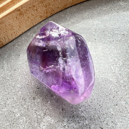彩虹紫水晶隨形

【 棲於光影間的彩虹 】｜ 紫水晶隨形

這不只是一顆礦石，更像是大自然隨手裁下的一片靜謐光影。

紫水晶深邃且溫柔的色澤，在不規則的隨形切割下，展現出最原始、不經修飾的生命力。當自然光線穿透晶體，內部的天然冰裂縫隙彷彿成了光的稜鏡，在特定角度下綻放出璀璨的彩虹光芒，那是藏在時間深處的驚喜。