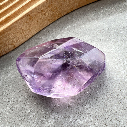 彩虹紫水晶隨形

【 棲於光影間的彩虹 】｜ 紫水晶隨形

這不只是一顆礦石，更像是大自然隨手裁下的一片靜謐光影。

紫水晶深邃且溫柔的色澤，在不規則的隨形切割下，展現出最原始、不經修飾的生命力。當自然光線穿透晶體，內部的天然冰裂縫隙彷彿成了光的稜鏡，在特定角度下綻放出璀璨的彩虹光芒，那是藏在時間深處的驚喜。