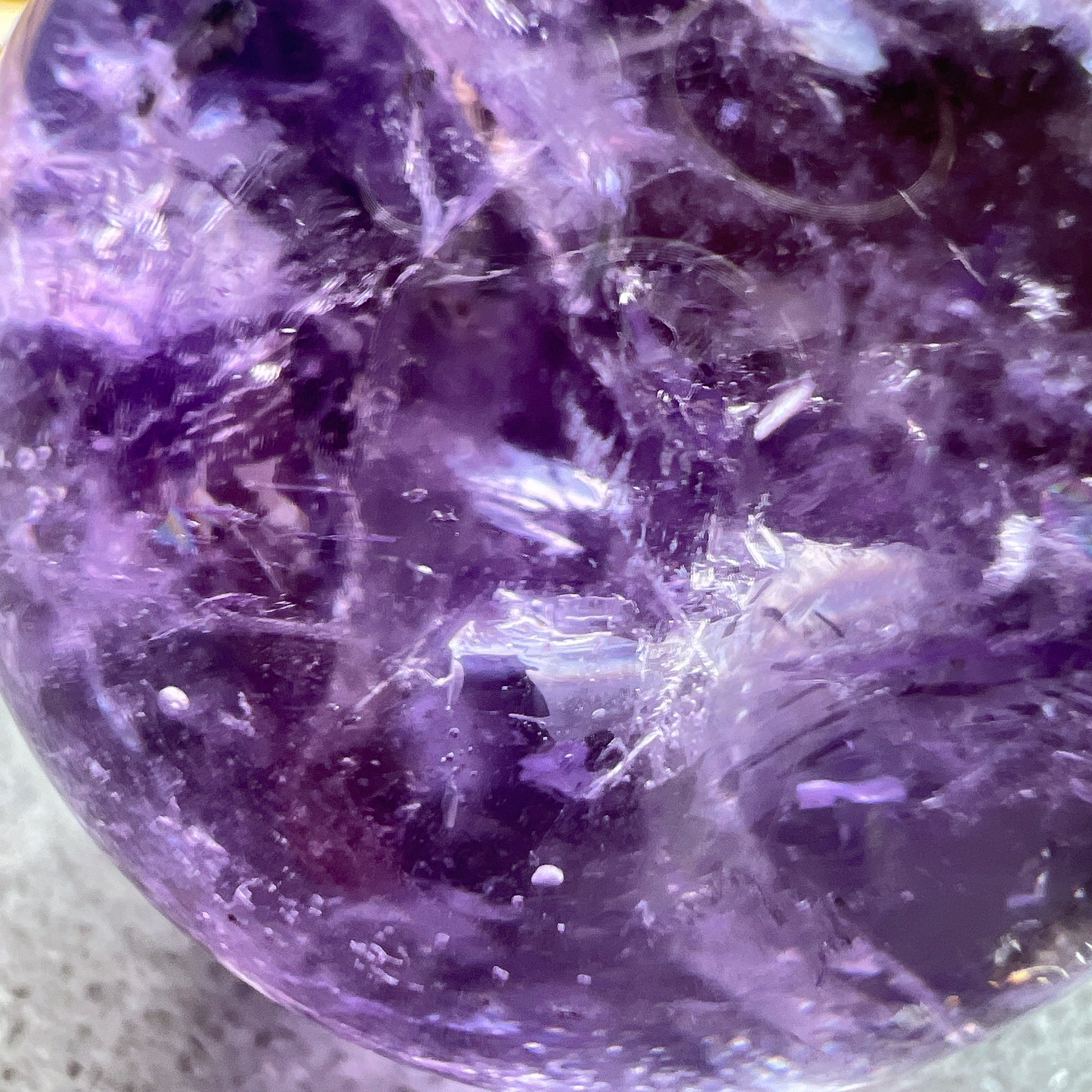 紫水晶
【 圓潤之境，光之詩意 】｜ 彩虹光紫水晶球

如果說隨形是自然的率性，那麼水晶球便是大地最圓滿的溫柔。

這顆紫水晶球在純淨的紫色晶體中，包裹著歲月沈澱的天然冰裂紋與雲霧。 透過自然光線的折射，球體內部在不同角度下會閃耀出如夢似幻的彩虹光芒，彷彿將雨後的晴空濃縮於指尖。