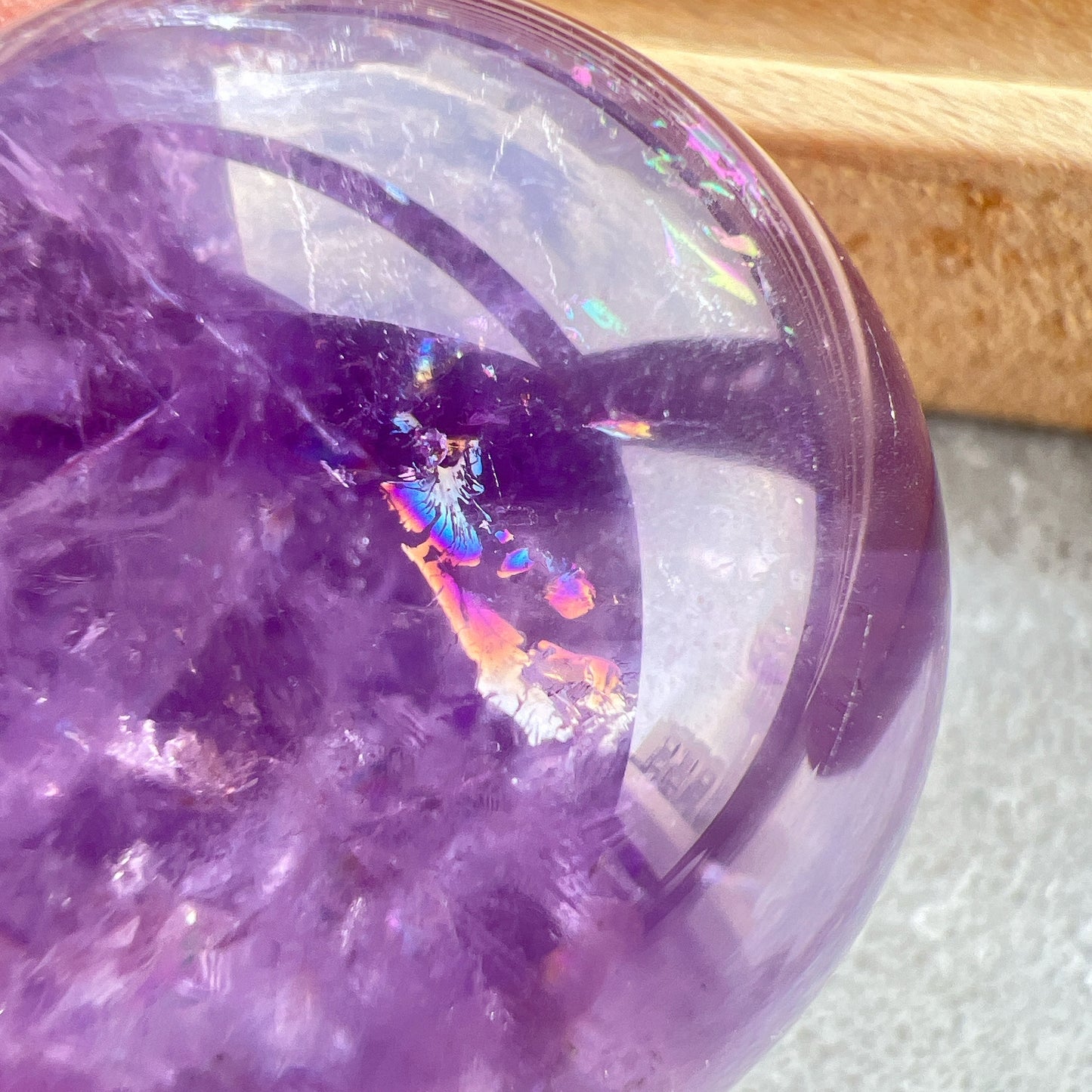 紫水晶
【 圓潤之境，光之詩意 】｜ 彩虹光紫水晶球

如果說隨形是自然的率性，那麼水晶球便是大地最圓滿的溫柔。

這顆紫水晶球在純淨的紫色晶體中，包裹著歲月沈澱的天然冰裂紋與雲霧。 透過自然光線的折射，球體內部在不同角度下會閃耀出如夢似幻的彩虹光芒，彷彿將雨後的晴空濃縮於指尖。