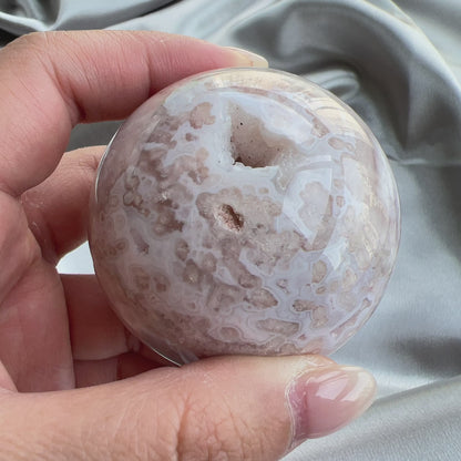 紫晶櫻花瑪瑙開口笑球  這是一個開口笑，是紫晶櫻花瑪瑙球，淡淡的紫粉紅色，再配上清晰的白瑪瑙紋💕  瑪瑙-Agate品種繁多，整個瑪瑙家族十分龐大。其中一種瑪瑙充滿溫柔優雅之美，深受女仕們喜愛，就是櫻花瑪瑙 - Blossoms Agate🌸  櫻花瑪瑙被視為寶石中的「第三眼」，靈性十足，象徵友善與愛心，也代表希望。  櫻花瑪瑙晶體內含粉白色、猶如朵朵盛開之櫻花的共生礦，每枝形態獨一無二，為人帶來溫柔細膩的內涵，會令人要停下來慢慢欣賞佢嘅美。  -能令人精神放鬆，減少失眠症狀  -瑪瑙具有平衡，穩定及保護的作用  -也是護身符及辟邪物，有保平安功效  -瑪瑙維持身心和諧，增強愛、忠誠及勇氣   