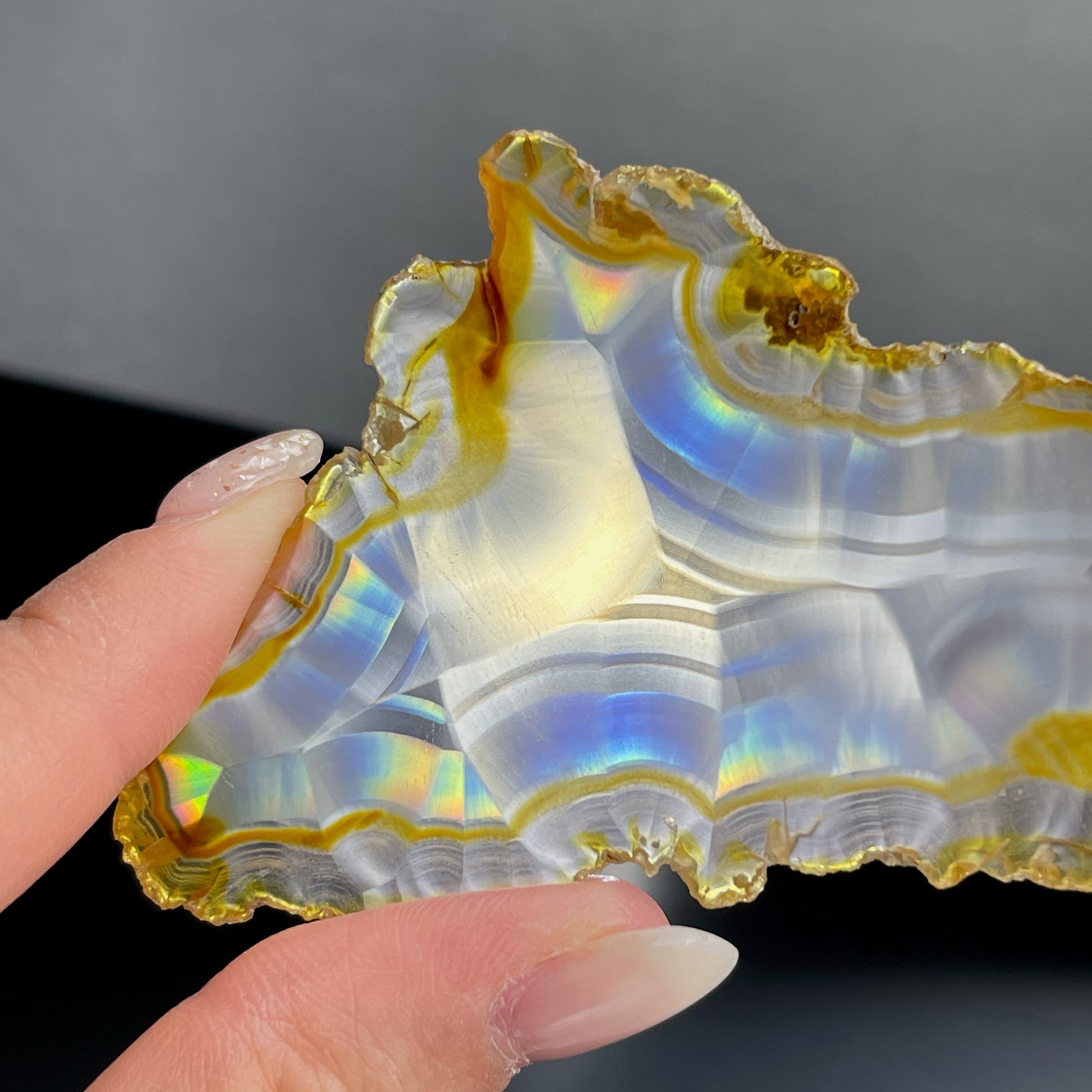 虹彩瑪瑙是一種細帶狀、半透明的石髓 (Chalcedony)，並且可將透射光分解成為光譜顏色。”Iris”意為”彩虹”或”虹彩虹色的”，源自於希臘彩虹女神的名字。  Iris agate is a finely-banded, translucent variety of chalcedony that breaks up transmitted light into spectral colors. The word “Iris” means “rainbow” or “to make iridescent” and is derived from the name of the Greek goddess of the rainbow.     *以上資料轉載自 “GIA Hong Kong - Jul 2021”