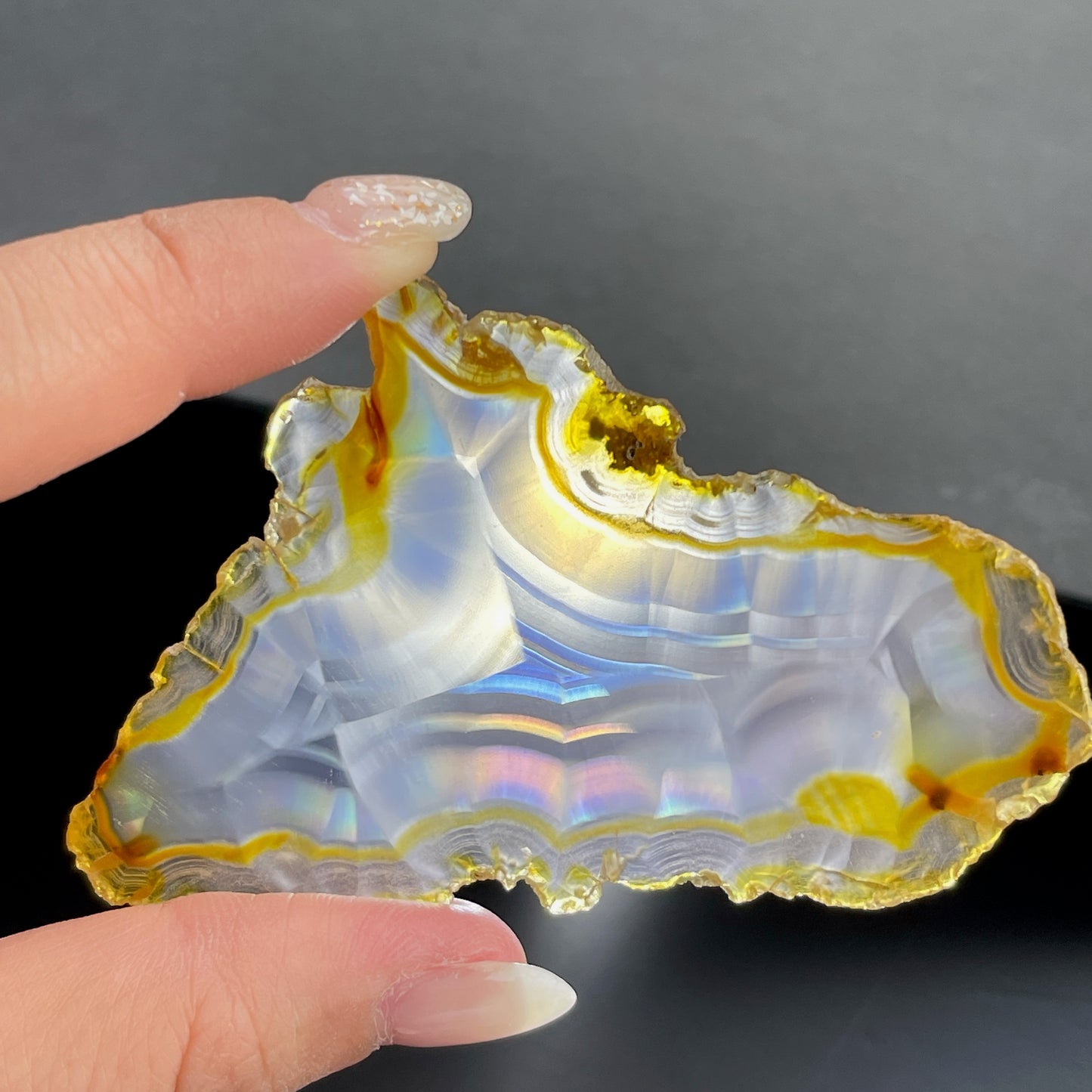 虹彩瑪瑙是一種細帶狀、半透明的石髓 (Chalcedony)，並且可將透射光分解成為光譜顏色。”Iris”意為”彩虹”或”虹彩虹色的”，源自於希臘彩虹女神的名字。  Iris agate is a finely-banded, translucent variety of chalcedony that breaks up transmitted light into spectral colors. The word “Iris” means “rainbow” or “to make iridescent” and is derived from the name of the Greek goddess of the rainbow.     *以上資料轉載自 “GIA Hong Kong - Jul 2021”