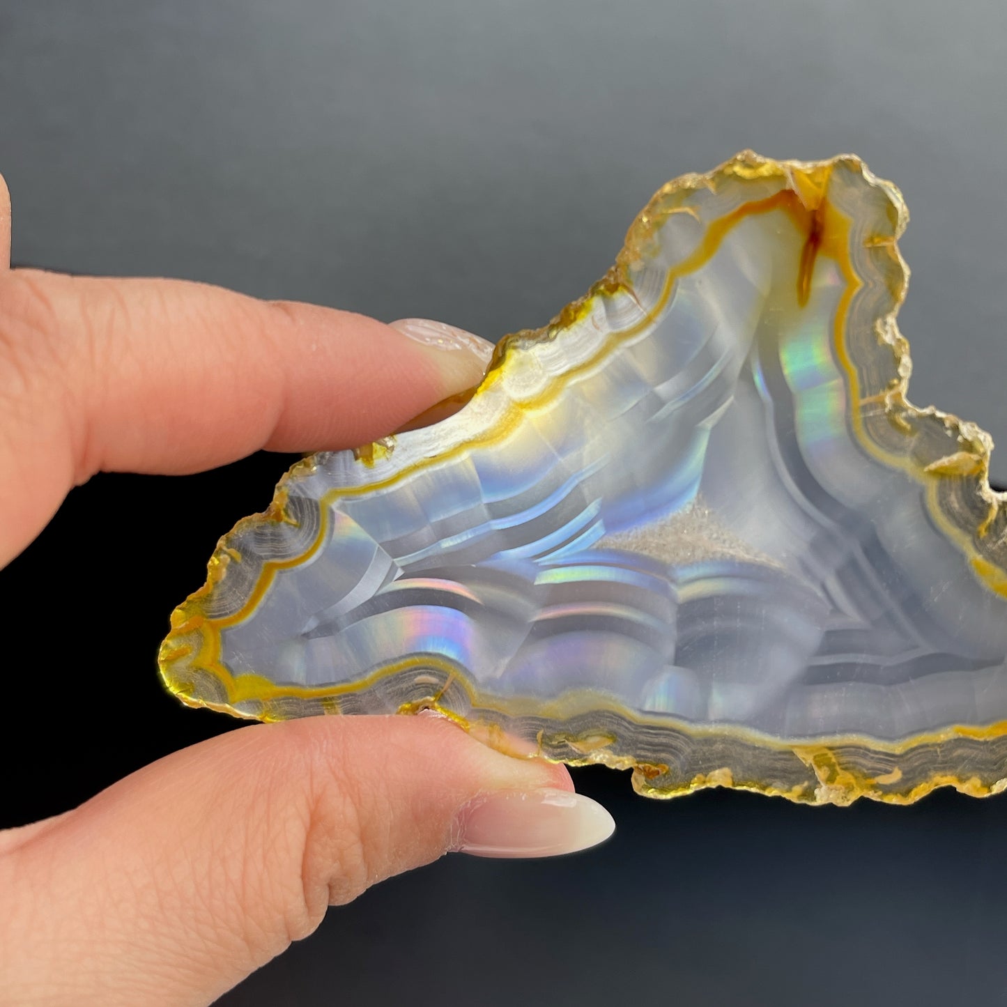 虹彩瑪瑙是一種細帶狀、半透明的石髓 (Chalcedony)，並且可將透射光分解成為光譜顏色。”Iris”意為”彩虹”或”虹彩虹色的”，源自於希臘彩虹女神的名字。  Iris agate is a finely-banded, translucent variety of chalcedony that breaks up transmitted light into spectral colors. The word “Iris” means “rainbow” or “to make iridescent” and is derived from the name of the Greek goddess of the rainbow.     *以上資料轉載自 “GIA Hong Kong - Jul 2021”