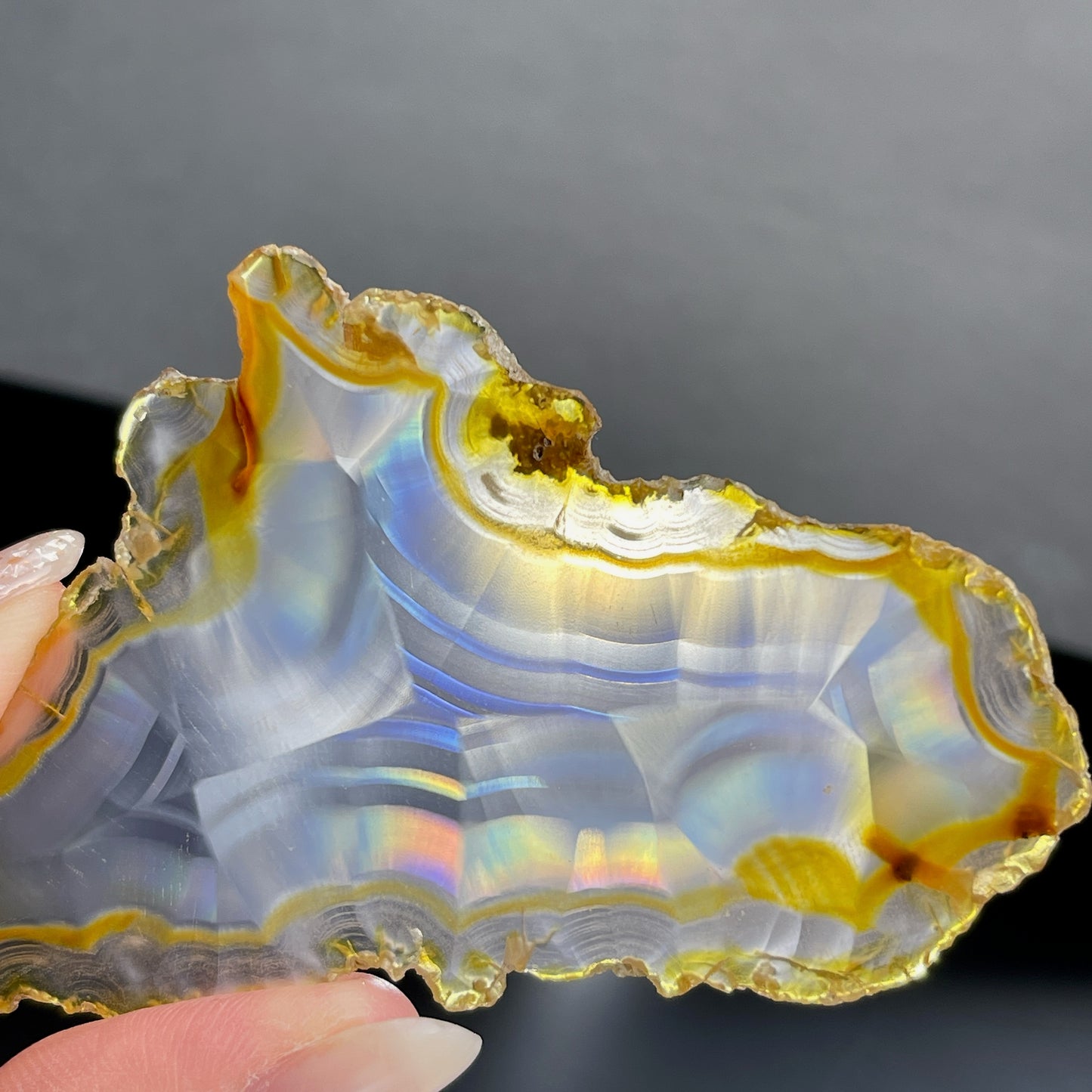 虹彩瑪瑙是一種細帶狀、半透明的石髓 (Chalcedony)，並且可將透射光分解成為光譜顏色。”Iris”意為”彩虹”或”虹彩虹色的”，源自於希臘彩虹女神的名字。  Iris agate is a finely-banded, translucent variety of chalcedony that breaks up transmitted light into spectral colors. The word “Iris” means “rainbow” or “to make iridescent” and is derived from the name of the Greek goddess of the rainbow.     *以上資料轉載自 “GIA Hong Kong - Jul 2021”