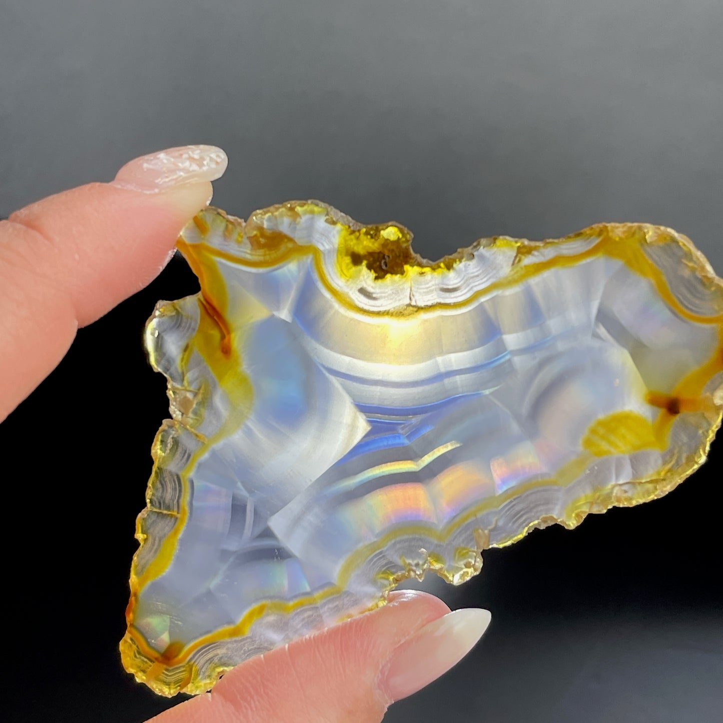 虹彩瑪瑙是一種細帶狀、半透明的石髓 (Chalcedony)，並且可將透射光分解成為光譜顏色。”Iris”意為”彩虹”或”虹彩虹色的”，源自於希臘彩虹女神的名字。  Iris agate is a finely-banded, translucent variety of chalcedony that breaks up transmitted light into spectral colors. The word “Iris” means “rainbow” or “to make iridescent” and is derived from the name of the Greek goddess of the rainbow.     *以上資料轉載自 “GIA Hong Kong - Jul 2021”