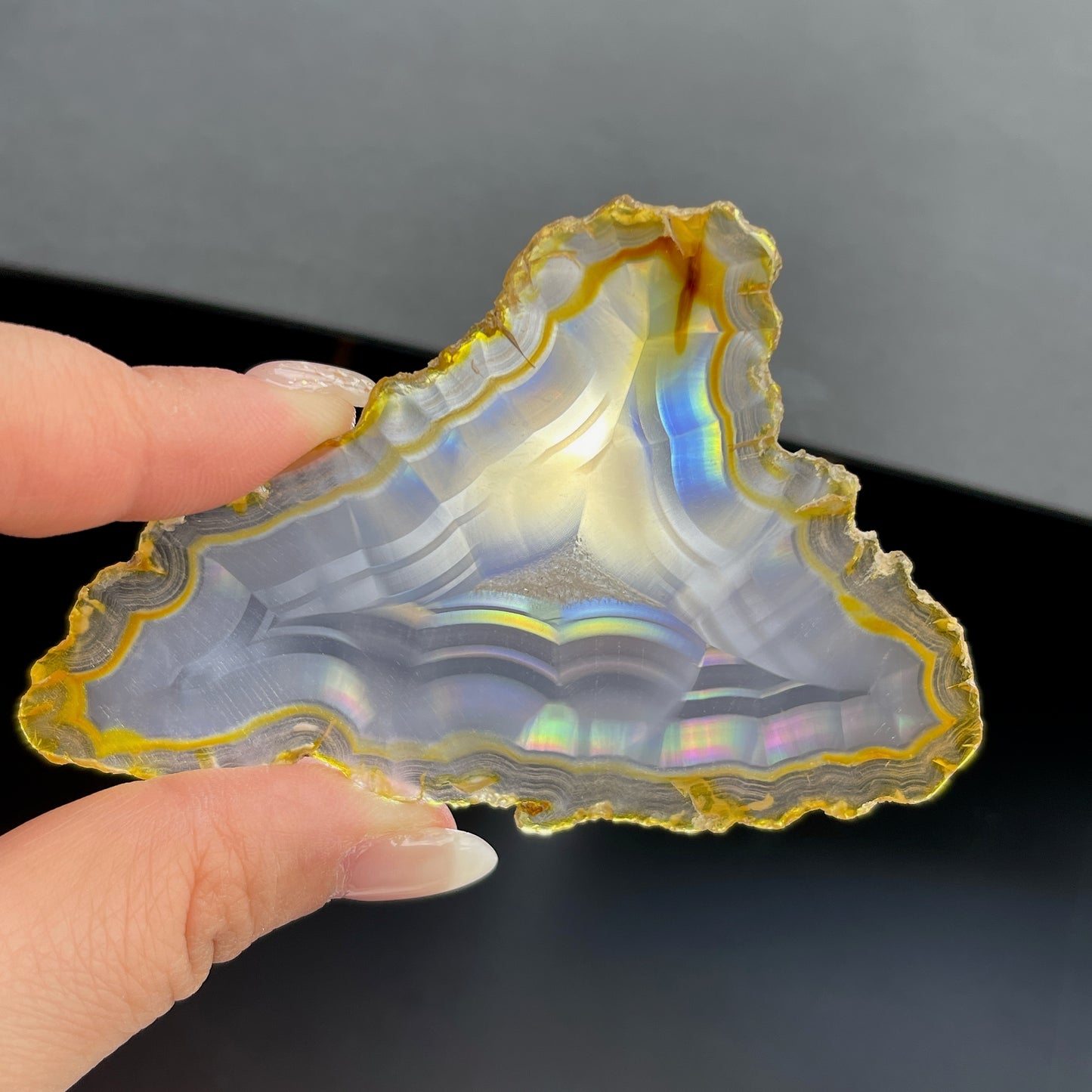 虹彩瑪瑙是一種細帶狀、半透明的石髓 (Chalcedony)，並且可將透射光分解成為光譜顏色。”Iris”意為”彩虹”或”虹彩虹色的”，源自於希臘彩虹女神的名字。  Iris agate is a finely-banded, translucent variety of chalcedony that breaks up transmitted light into spectral colors. The word “Iris” means “rainbow” or “to make iridescent” and is derived from the name of the Greek goddess of the rainbow.     *以上資料轉載自 “GIA Hong Kong - Jul 2021”