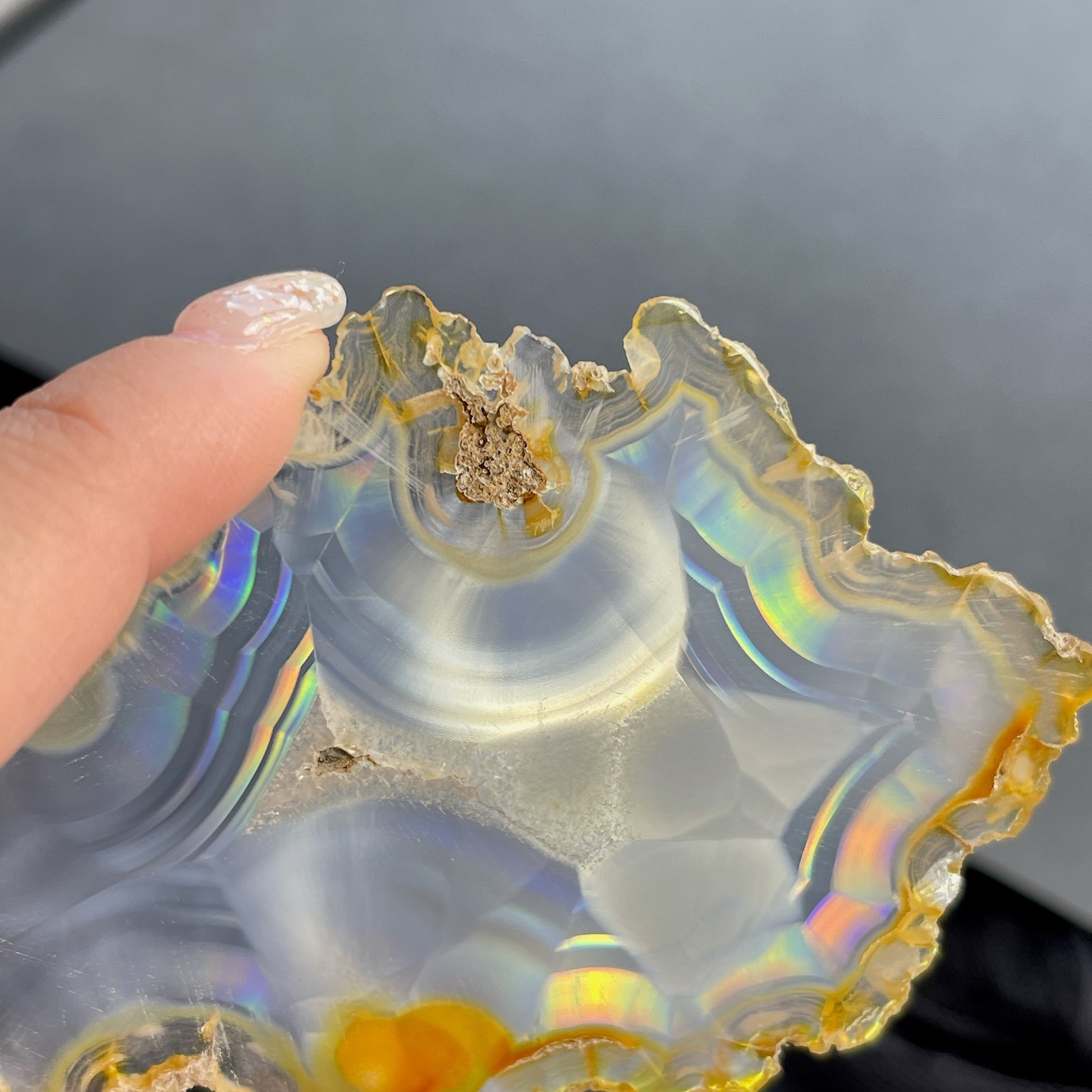 虹彩瑪瑙是一種細帶狀、半透明的石髓 (Chalcedony)，並且可將透射光分解成為光譜顏色。”Iris”意為”彩虹”或”虹彩虹色的”，源自於希臘彩虹女神的名字。  Iris agate is a finely-banded, translucent variety of chalcedony that breaks up transmitted light into spectral colors. The word “Iris” means “rainbow” or “to make iridescent” and is derived from the name of the Greek goddess of the rainbow.     *以上資料轉載自 “GIA Hong Kong - Jul 2021”