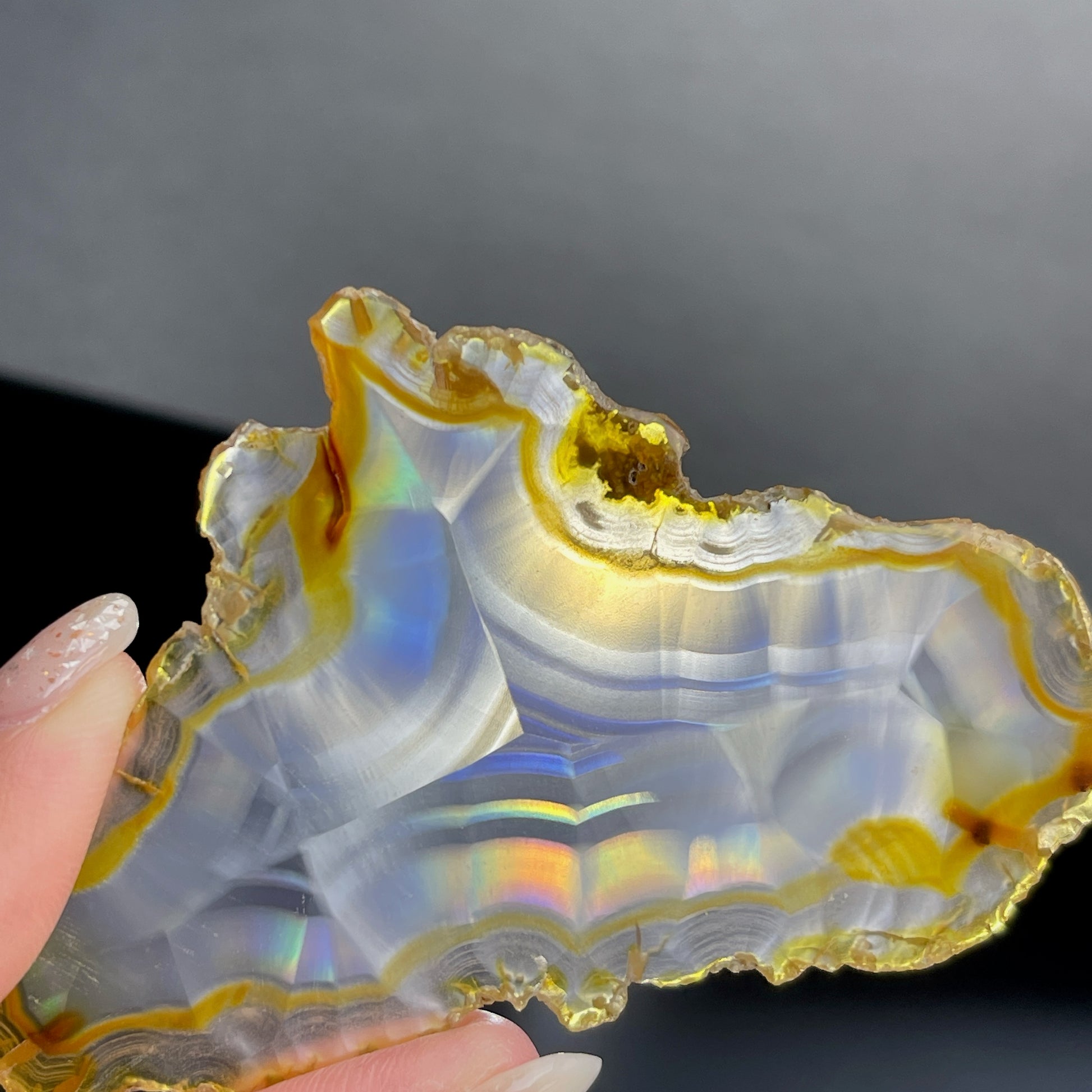 虹彩瑪瑙是一種細帶狀、半透明的石髓 (Chalcedony)，並且可將透射光分解成為光譜顏色。”Iris”意為”彩虹”或”虹彩虹色的”，源自於希臘彩虹女神的名字。  Iris agate is a finely-banded, translucent variety of chalcedony that breaks up transmitted light into spectral colors. The word “Iris” means “rainbow” or “to make iridescent” and is derived from the name of the Greek goddess of the rainbow.     *以上資料轉載自 “GIA Hong Kong - Jul 2021”