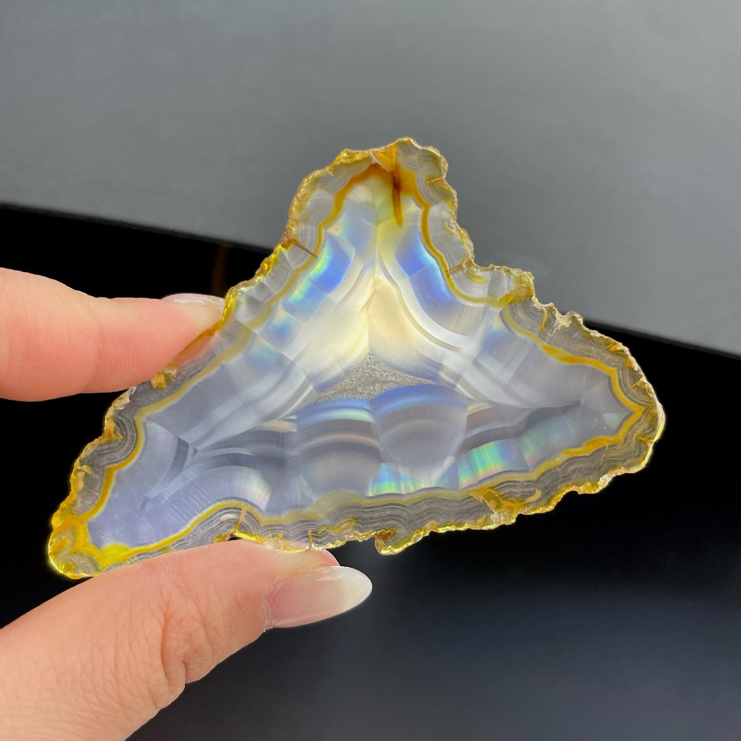 虹彩瑪瑙是一種細帶狀、半透明的石髓 (Chalcedony)，並且可將透射光分解成為光譜顏色。”Iris”意為”彩虹”或”虹彩虹色的”，源自於希臘彩虹女神的名字。  Iris agate is a finely-banded, translucent variety of chalcedony that breaks up transmitted light into spectral colors. The word “Iris” means “rainbow” or “to make iridescent” and is derived from the name of the Greek goddess of the rainbow.     *以上資料轉載自 “GIA Hong Kong - Jul 2021”