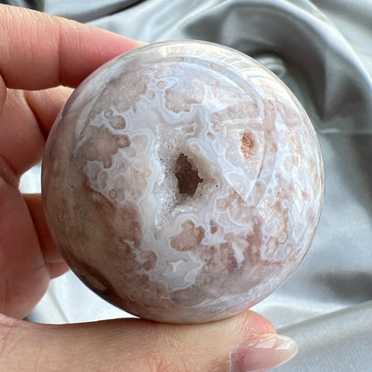 紫晶櫻花瑪瑙開口笑球  這是一個開口笑，是紫晶櫻花瑪瑙球，淡淡的紫粉紅色，再配上清晰的白瑪瑙紋💕  瑪瑙-Agate品種繁多，整個瑪瑙家族十分龐大。其中一種瑪瑙充滿溫柔優雅之美，深受女仕們喜愛，就是櫻花瑪瑙 - Blossoms Agate🌸  櫻花瑪瑙被視為寶石中的「第三眼」，靈性十足，象徵友善與愛心，也代表希望。  櫻花瑪瑙晶體內含粉白色、猶如朵朵盛開之櫻花的共生礦，每枝形態獨一無二，為人帶來溫柔細膩的內涵，會令人要停下來慢慢欣賞佢嘅美。  -能令人精神放鬆，減少失眠症狀  -瑪瑙具有平衡，穩定及保護的作用  -也是護身符及辟邪物，有保平安功效  -瑪瑙維持身心和諧，增強愛、忠誠及勇氣   