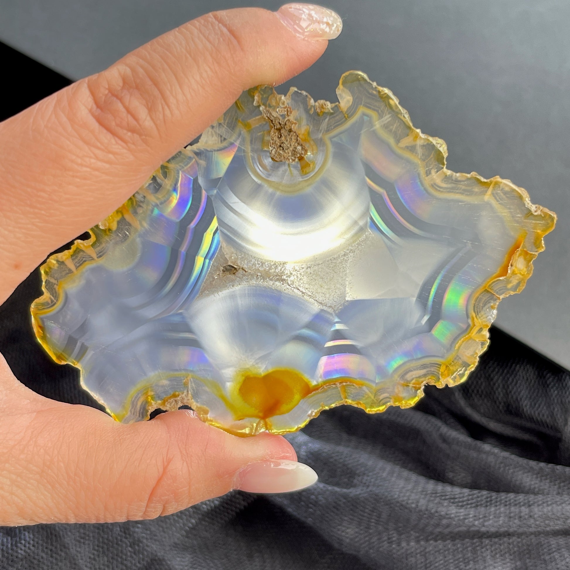 虹彩瑪瑙是一種細帶狀、半透明的石髓 (Chalcedony)，並且可將透射光分解成為光譜顏色。”Iris”意為”彩虹”或”虹彩虹色的”，源自於希臘彩虹女神的名字。  Iris agate is a finely-banded, translucent variety of chalcedony that breaks up transmitted light into spectral colors. The word “Iris” means “rainbow” or “to make iridescent” and is derived from the name of the Greek goddess of the rainbow.     *以上資料轉載自 “GIA Hong Kong - Jul 2021”